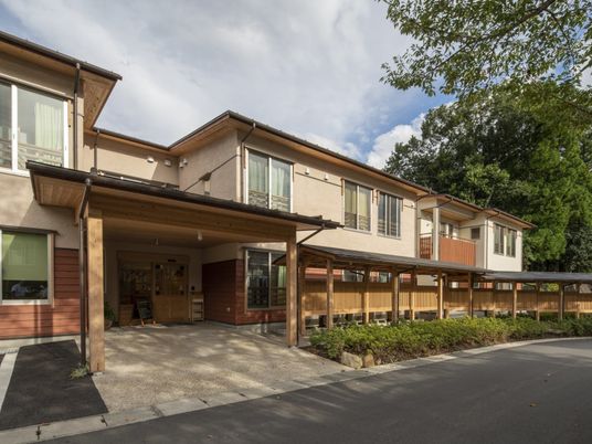 和の雰囲気漂う2階建ての建物。玄関部分についた屋根は、玄関の横につながる通路にも続いている。