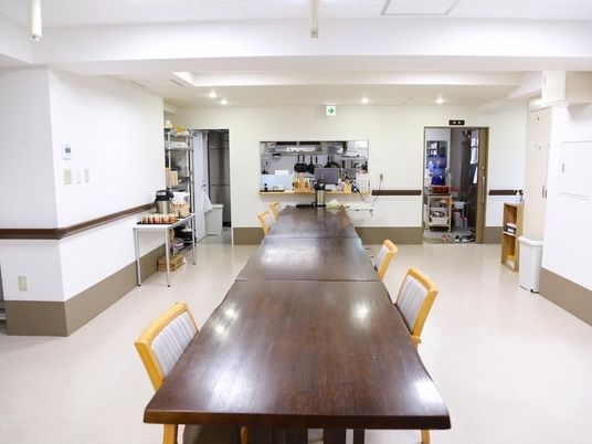 食堂には大きなダークブラウンのテーブルセットが置かれ、壁には手すりが付いていて、右側には長テーブルがある。