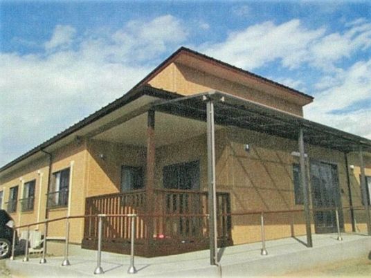 ブラウンを基調とした木造建築。温かみのある雰囲気で、玄関周りには手すり付きのスロープがある。