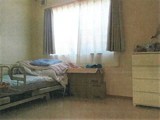 ベッドやたんすが置かれた居室。カーテンが付いた大きな窓がある。