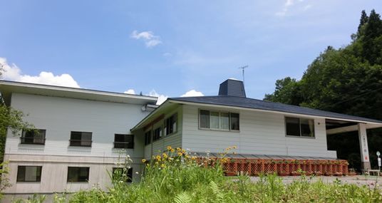 ２階建ての建物は白を基調とし、周辺には自然が多くある。