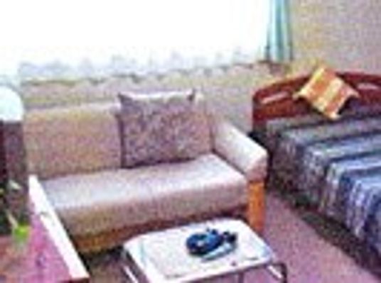 二人掛けのソファとベッドがある小さなワンルームの様子。施設内の居室の写真