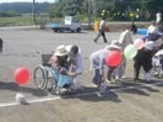 広い敷地内で運動会のような催し物に興じる高齢者とスタッフの様子
