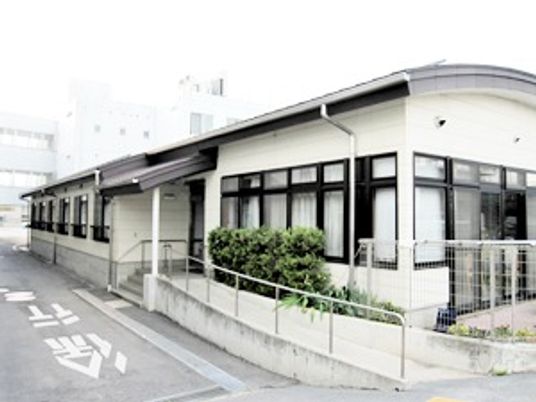 大きな病院がバックにある平屋建ての建物の玄関にはスロープが付いている。