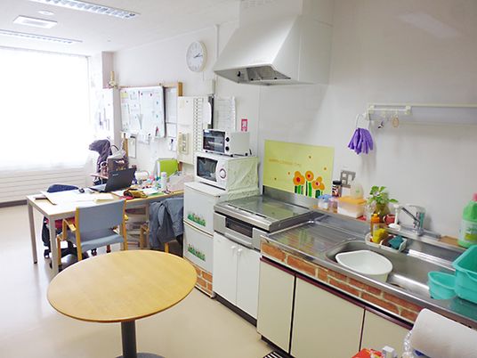 生活感あふれるキッチンにはIHクッキングヒーターがあり、奥には事務作業をするテーブルがある。