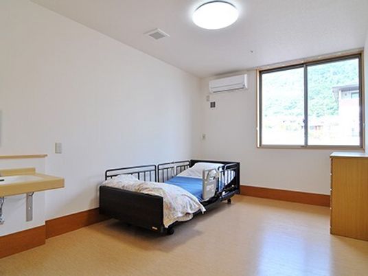 介護ベッドが部屋には車いす対応の洗面所があり、大きな窓やエアコンも付いている。