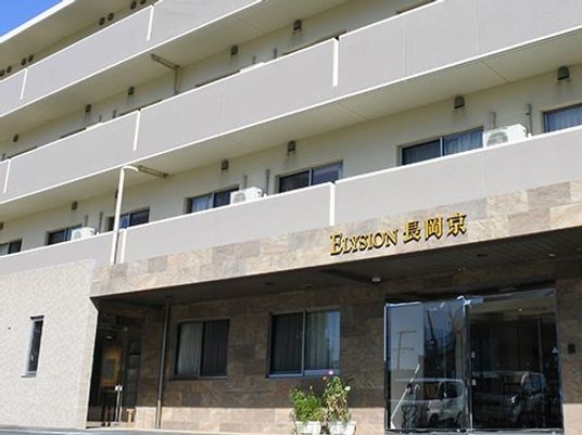 グレーを基調にした4階建て他の建物。玄関周辺には鉢植えも置かれ、段差もない。