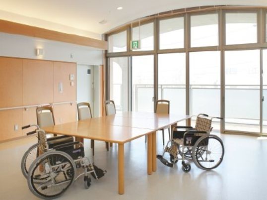 ダイニングテーブルを囲んで椅子と車いすがセットされていて、大きな窓が付いている。
