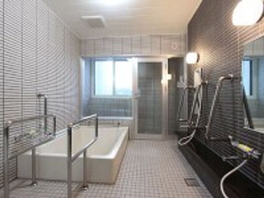 手すりがついた施設内の浴室の様子。プールのような広めの浴槽がある様子
