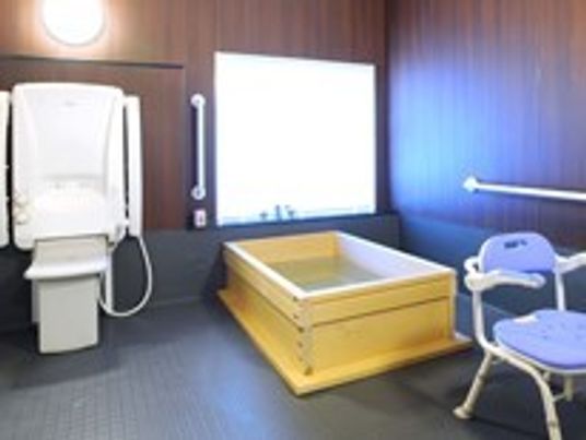 大きな窓が付いた浴室には木製の浴槽や介護用シャワーが付いている。