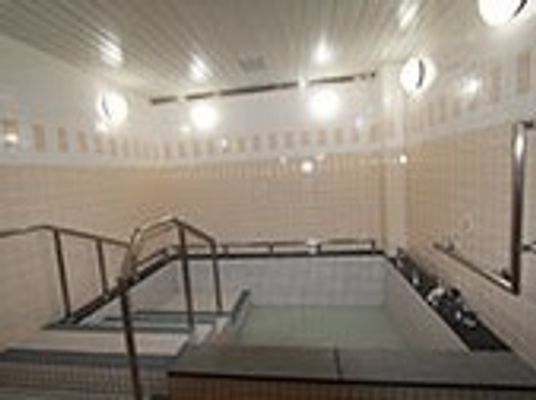 大きな浴槽は右側にある手すり付きの階段を下りて浴槽に浸かるタイプ。ピンクのタイルが明るい雰囲気をプラス。
