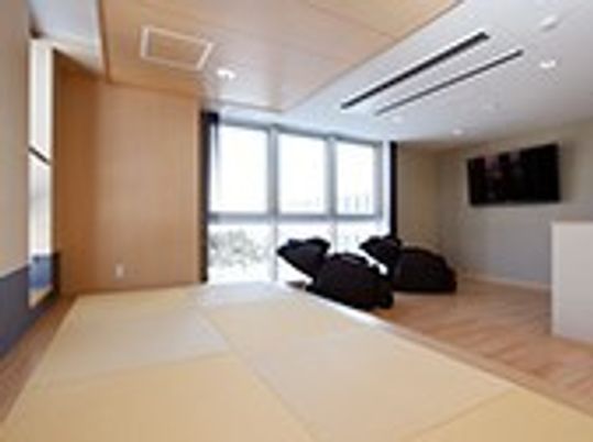 大浴場の近くにある休憩場。奥にはテレビと黒いマッサージチェア、手前には広い畳スペースがある。