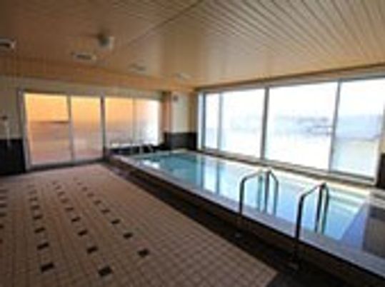 大浴場に設置された長方形の大きな浴槽。窓の外には住みなれた街の風景が広がっている。