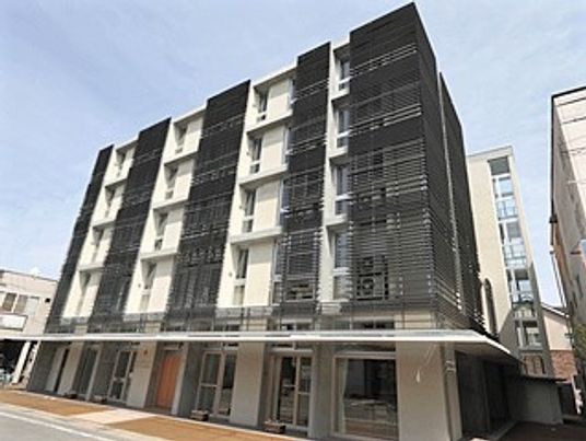 5階建ての建物はモノトーンで１階部分には屋根が付いている。