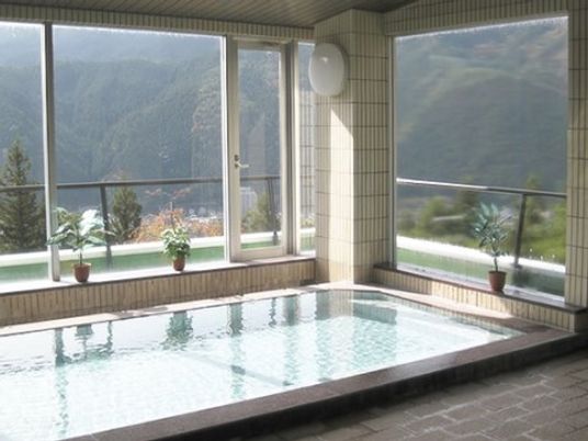 ファミリアシリーズの浴室。建物の上部に位置し、大きな窓が全面にあるため、緑豊かな景色を眺めながら温泉が楽しめる。