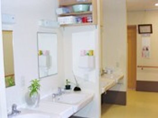 洗面所が複数並び、鏡が設置され、車いす対応のデザイン。壁には手すりが設置されている。