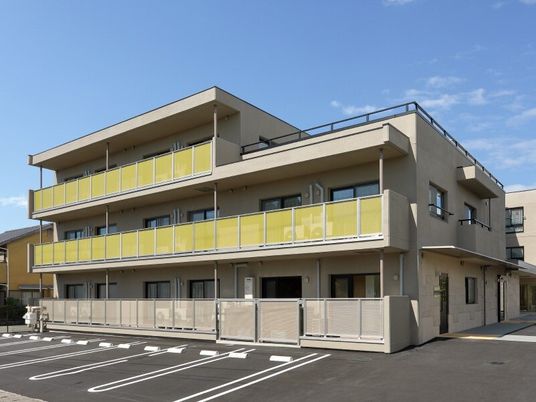 大きな駐車場がある3階建ての建物の各フロアにベランダが付いている。3階部分には屋上もある。