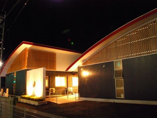 やわらかい色合いの照明でライトアップされた施設の外観写真