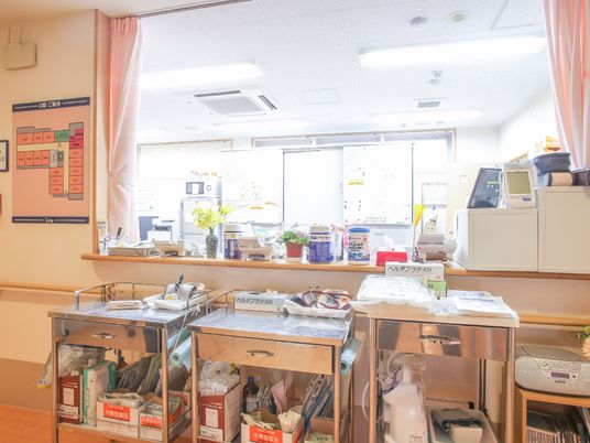 ステンレス製の移動式のラックが３台スタッフステーションの前に並んでいる。スタッフステーションは電気が付いていて明るい。