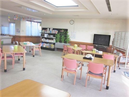 四人掛けのテーブルと椅子が複数組並んでいる施設内のリビングスペース