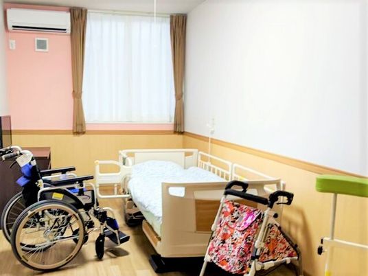 車いすと介護用ベッド、テレビやエアコンなどが置いてある施設内の居室