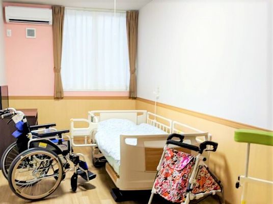 車いすと介護用ベッド、テレビやエアコンなどが置いてある施設内の居室
