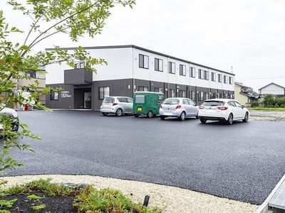 ２階建ての建物。玄関には屋根が付き、モノトーンで落ち着いた雰囲気。