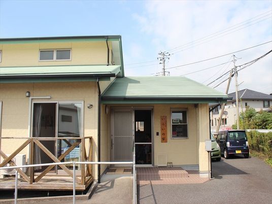 平屋建ての建物。三角屋根が付き玄関にはスロープも設置され、駐車場も付いている。