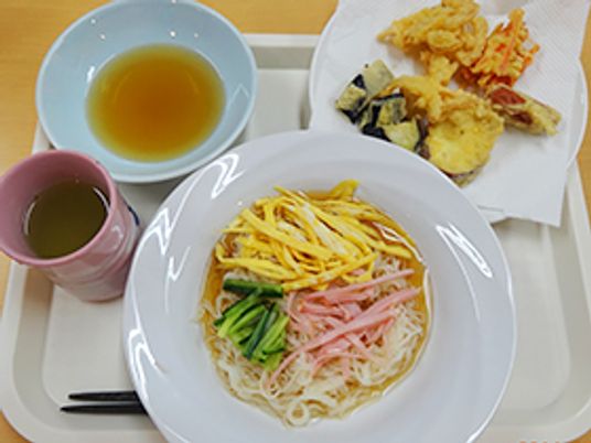 麺類やお茶、おかずなどが並んでいる彩り豊かなメニューの写真。施設内で用意されている食事の写真