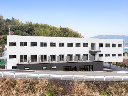 白を基調とした3階建ての建物は自然に囲まれ、テラスも付いている。