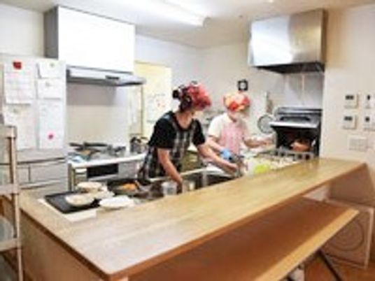 リビングに併設したキッチンで調理しているスタッフの様子。家庭用サイズの小さなキッチン