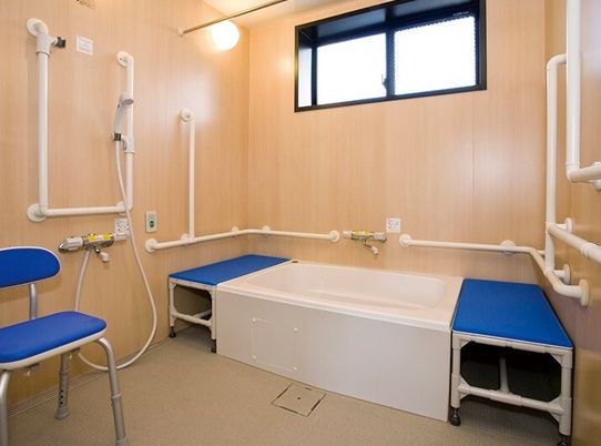 両サイドにベンチが付いた一人用の浴槽が設置された浴室にはたくさんの手すりが付き、シャワーのそばにはシャワーチェアもある。