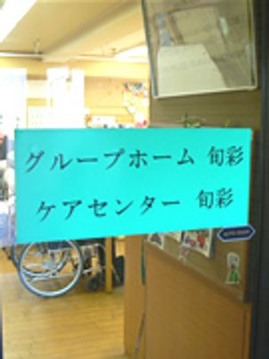 グループホームと小規模多機能ホームの名前が大きく画面に書かれている。車いすの入居者が見える。