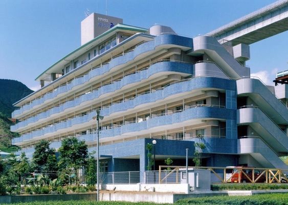 ブルー系の大きな建物は自然に囲まれ、各フロアにベランダがあり、屋外の階段もついている。