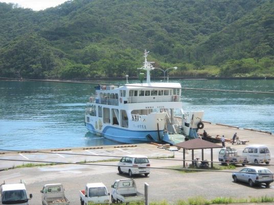 港にフェリーが着いた時の様子。数名の乗客が乗り降りをしていて、手前の休憩所にも人が座っている。