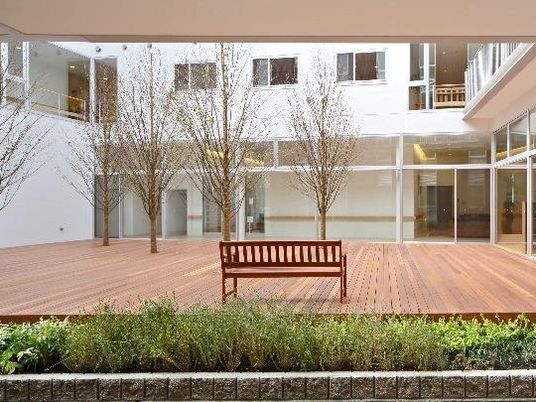 ウッドデッキの中庭には木製のベンチが置かれ、周辺には木の低い木が植えられている。