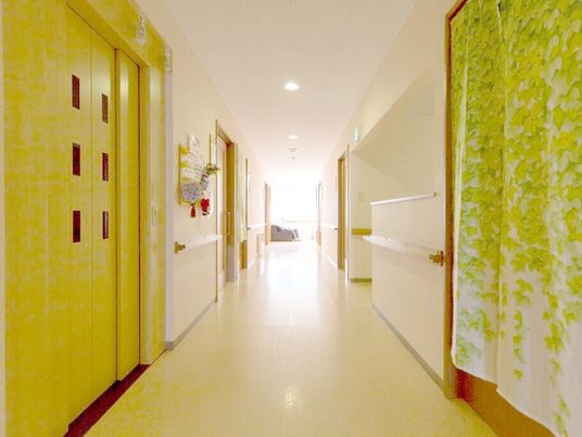 施設内のバリアフリー対応の廊下の様子。手すりがついた壁とエレベーター