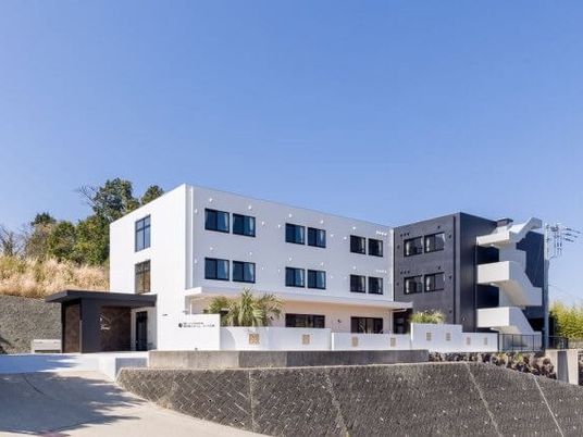 エル字型の3階建ての建物の周りには草木が植えられ、小高い丘に建っていて、日当たり良好。