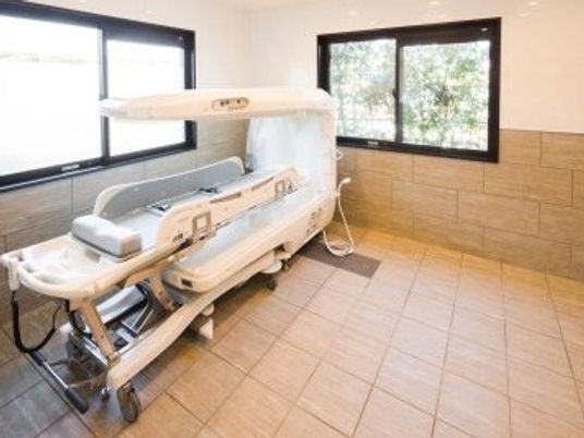 寝たまま入浴できる寝台浴が設置されているタイル張りの浴室には大きな窓が2カ所についている。
