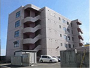 施設外観。５階建てでベージュを基調とした建物