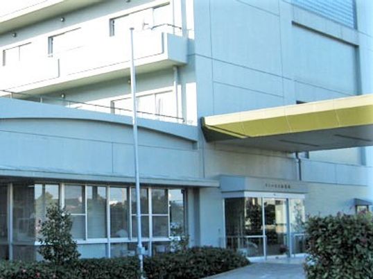 4階建ての白い建物には窓が多くつき、玄関には屋根が設置されている。