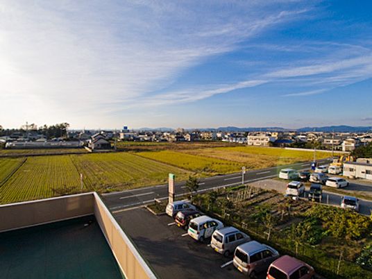 施設の屋上から周辺を見渡している写真。駐車場と周辺の田んぼの様子が移っている