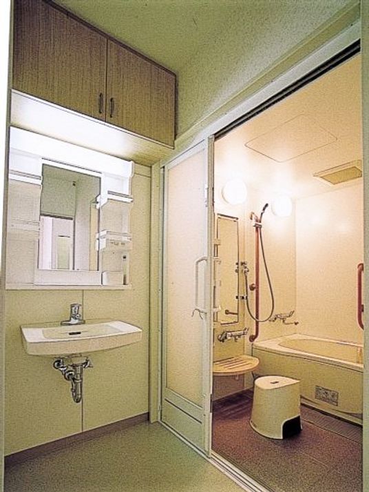 一人用の浴槽が置かれた浴室。手すりやシャワーも設置され、脱衣所もついている。