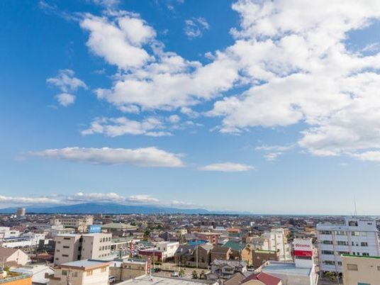 青空が写っている写真。高台から街をみおろしたような風景写真