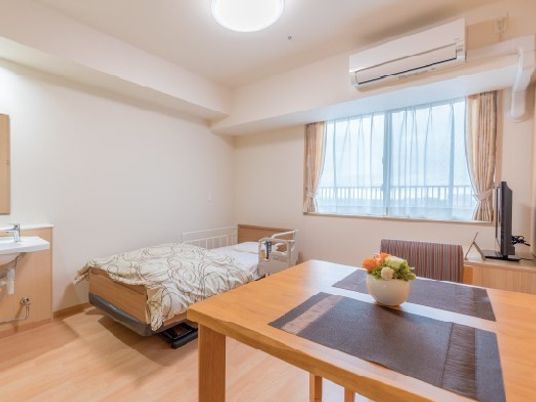 エアコン、洗面台、いす、ベッドなどが置いてある一人用の部屋の様子