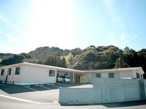 日当たりのいい場所に建っている平屋建ての建物。緑が周辺に多くあり、敷地内には駐車場がある。