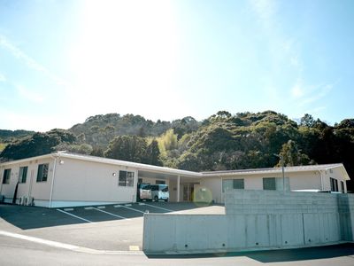 日当たりのいい場所に建っている平屋建ての建物。緑が周辺に多くあり、敷地内には駐車場がある。
