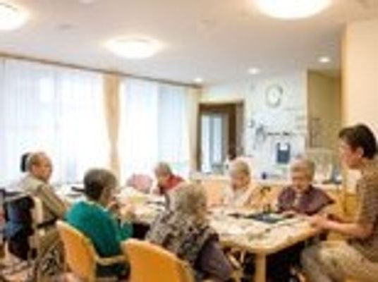 入居者が集まっているテーブルに男性スタッフも一緒に座り、明るい雰囲気中和やかに過ごしている。