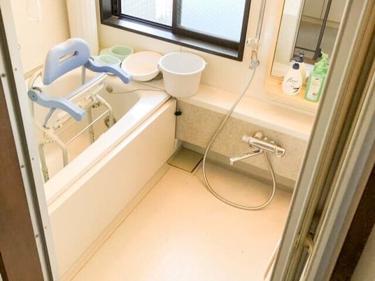 シャワーが付いた一人用の浴槽が設置された浴室。浴槽内にはたたまれたシャワーチェアが入っている。