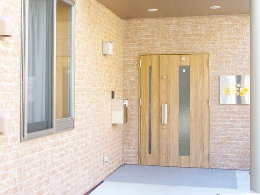 普通の過程のような玄関部分。左側に窓、正面には施設名がある